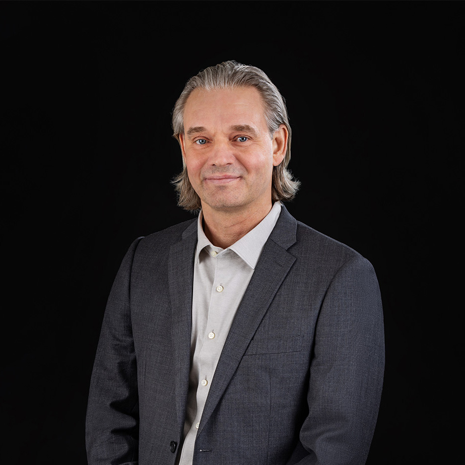 Porträtt av en man i kostym, fotograferad mot en svart bakgrund för tjänsten personalfoto.